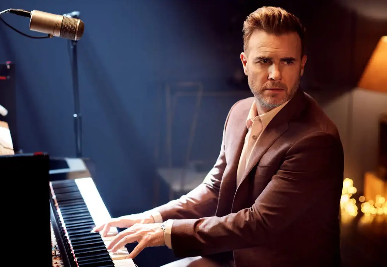 Gary Barlow seated at a piano, for P&O Cruises