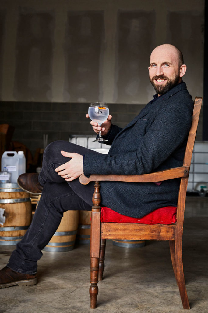 Man sat in old chair holding gin glass