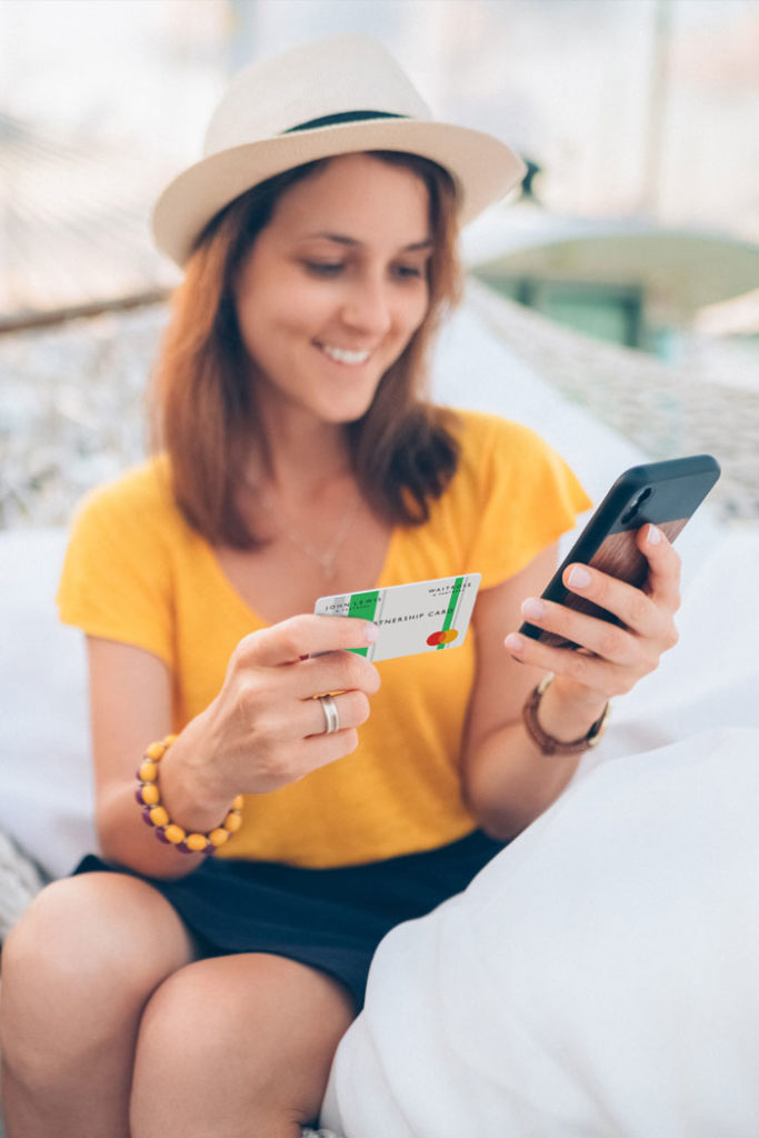 John Lewis Financial Services photo of woman looking at her phone while holding a credit card.