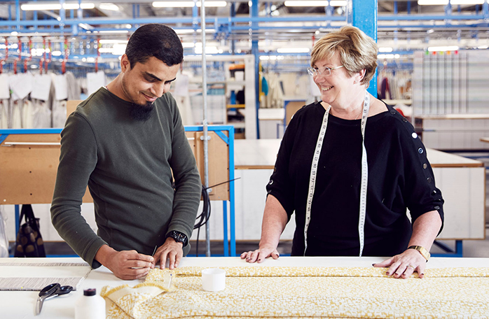 Two people talking whilst cutting fabric