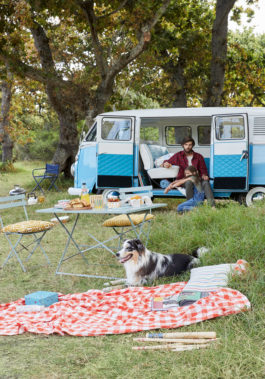 A man sits in his campervan with a dog