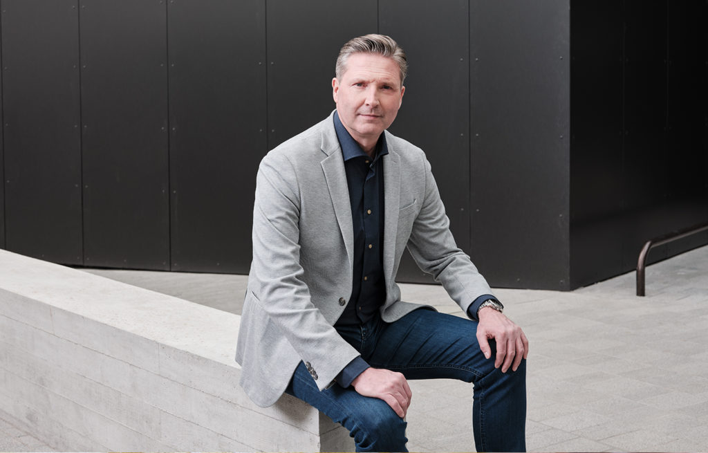 Man in suit sat in front of black building