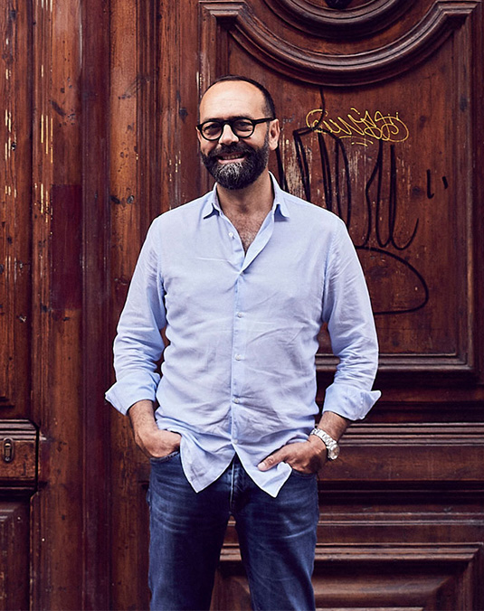 Man with hands in pockets stood in front of old wooden door